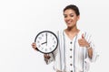 Beautiful african woman posing isolated over white wall background holding time clock