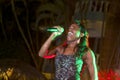 Beautiful African singer woman singing with colorful lights background with her microphone near her mouth Royalty Free Stock Photo