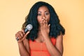 Beautiful african woman singing song using microphone covering mouth with hand, shocked and afraid for mistake Royalty Free Stock Photo