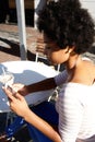 Beautiful african woman sitting at outside cafe using phone Royalty Free Stock Photo