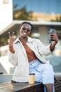 Beautiful African American woman taking selfie on mobile phone camera, showing victory sign. Emotional blogger streaming video Royalty Free Stock Photo