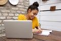 Beautiful african woman writing a book on cafe table with laptop Royalty Free Stock Photo