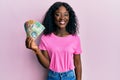 Beautiful african young woman holding australian dollars looking positive and happy standing and smiling with a confident smile Royalty Free Stock Photo