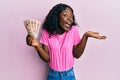 Beautiful african young woman holding 10 united kingdom pounds banknotes celebrating achievement with happy smile and winner