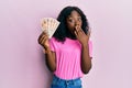 Beautiful african young woman holding 10 united kingdom pounds banknotes covering mouth with hand, shocked and afraid for mistake