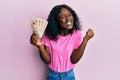 Beautiful african young woman holding 10 united kingdom pounds banknotes screaming proud, celebrating victory and success very