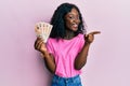 Beautiful african young woman holding 10 united kingdom pounds banknotes smiling happy pointing with hand and finger to the side