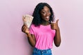 Beautiful african young woman holding 10 united kingdom pounds banknotes smiling happy and positive, thumb up doing excellent and