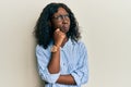 Beautiful african young woman wearing casual clothes and glasses thinking concentrated about doubt with finger on chin and looking Royalty Free Stock Photo