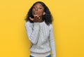 Beautiful african young woman wearing casual winter sweater looking at the camera blowing a kiss with hand on air being lovely and Royalty Free Stock Photo