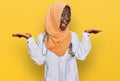 Beautiful african young woman wearing doctor uniform and hijab celebrating victory with happy smile and winner expression with Royalty Free Stock Photo