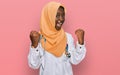 Beautiful african young woman wearing doctor uniform and hijab screaming proud, celebrating victory and success very excited with Royalty Free Stock Photo