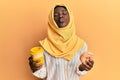 Beautiful african young woman wearing islamic hijab drinking a coffee using smartphone looking at the camera blowing a kiss being Royalty Free Stock Photo