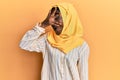 Beautiful african young woman wearing traditional islamic hijab scarf peeking in shock covering face and eyes with hand, looking Royalty Free Stock Photo