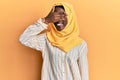 Beautiful african young woman wearing traditional islamic hijab scarf smiling and laughing with hand on face covering eyes for Royalty Free Stock Photo