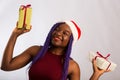 Beautiful Afro American girl in a dress and Santa hat is catching falling presents, looking at camera and smiling, isolated on Royalty Free Stock Photo