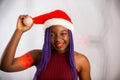 Beautiful Afro American girl in a dress and Santa hat is danci falling presents, looking at camera and smiling, isolated on white Royalty Free Stock Photo