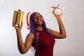 Beautiful Afro American girl in a dress and Santa hat is danci falling presents, looking at camera and smiling, isolated on white Royalty Free Stock Photo