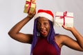 Beautiful Afro American girl in a dress and Santa hat is danci falling presents, looking at camera and smiling, isolated on white Royalty Free Stock Photo