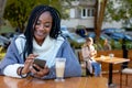 Beautiful Afro American woman chatting on her cell phone in a cafe. Royalty Free Stock Photo
