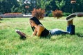Beautiful afro american woman reading book lying in grass in park Royalty Free Stock Photo