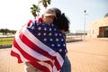 A beautiful Afro-American woman and an American soldier embrace wrapped in the American flag. The soldier has returned from war Royalty Free Stock Photo