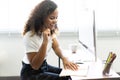 Beautiful afro american young woman smiling working on desktop while sitting at modern office Royalty Free Stock Photo