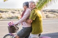 Beautiful aged couple of senior in vacation go both on an old bike and enjoy the summer sunlight. tropical place and country side