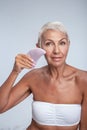 Beautiful aged lady holding a face cleaning tool to her face Royalty Free Stock Photo