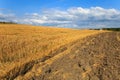 Beautiful landscape with freshly reaped wheat field and ploughed soil against blue sky with clouds Royalty Free Stock Photo