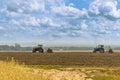 Beautiful agricultural landscape under the cloudy sky - two old tractors equipped with seeders.