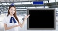 Beautiful Airline stewardess showing the blank TV screen in airport lobby Royalty Free Stock Photo