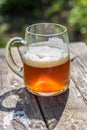 Beautiful amber glass of craft beer on rustic wood table out in garden