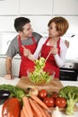 Beautiful American couple working at home kitchen in apron mixing vegetable salad smiling happy Royalty Free Stock Photo