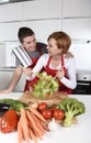 Beautiful American couple working at home kitchen in apron mixing vegetable salad smiling happy Royalty Free Stock Photo