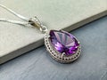 Beautiful amethyst pendant reflecting on gray surface Royalty Free Stock Photo