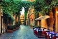 Old street in Rome with leafy vines and cafe tables, Italy Royalty Free Stock Photo