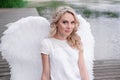 beautiful angel in white dress. Amazing blond woman with long curly hair and white wings. Royalty Free Stock Photo