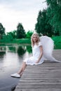 beautiful angel in white dress. Amazing blond woman with long curly hair and white wings. Royalty Free Stock Photo