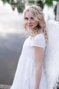 beautiful angel in white dress. Amazing blond woman with long curly hair and white wings. Royalty Free Stock Photo