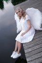 beautiful angel in white dress. Amazing blond woman with long curly hair and white wings. Royalty Free Stock Photo