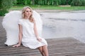 beautiful angel in white dress. Amazing blond woman with long curly hair and white wings. Royalty Free Stock Photo