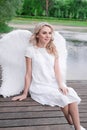 beautiful angel in white dress. Amazing blond woman with long curly hair and white wings. Royalty Free Stock Photo