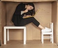 Beautiful, angry businesswoman sitting on a desk in a cramped paper office