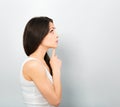 Beautiful angry suspicious thinking woman looking up on blue empty copy space background. Closeup