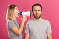 beautiful angry woman screaming with megaphone at confused man, isolated