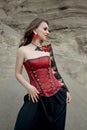 Beautiful anime woman in the sand. Red corset on the girl`s body. Bright red makeup on the face