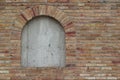 Beautiful antique brick wall texture sprinkled with hot pepper hued bricks of red, tan, pink and brown, with arched window Royalty Free Stock Photo