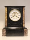 French antique black and brown marble clock with a white face.