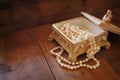 A beautiful antique golden jewelry box with natural white pearls on wooden table. retro filtered image Royalty Free Stock Photo